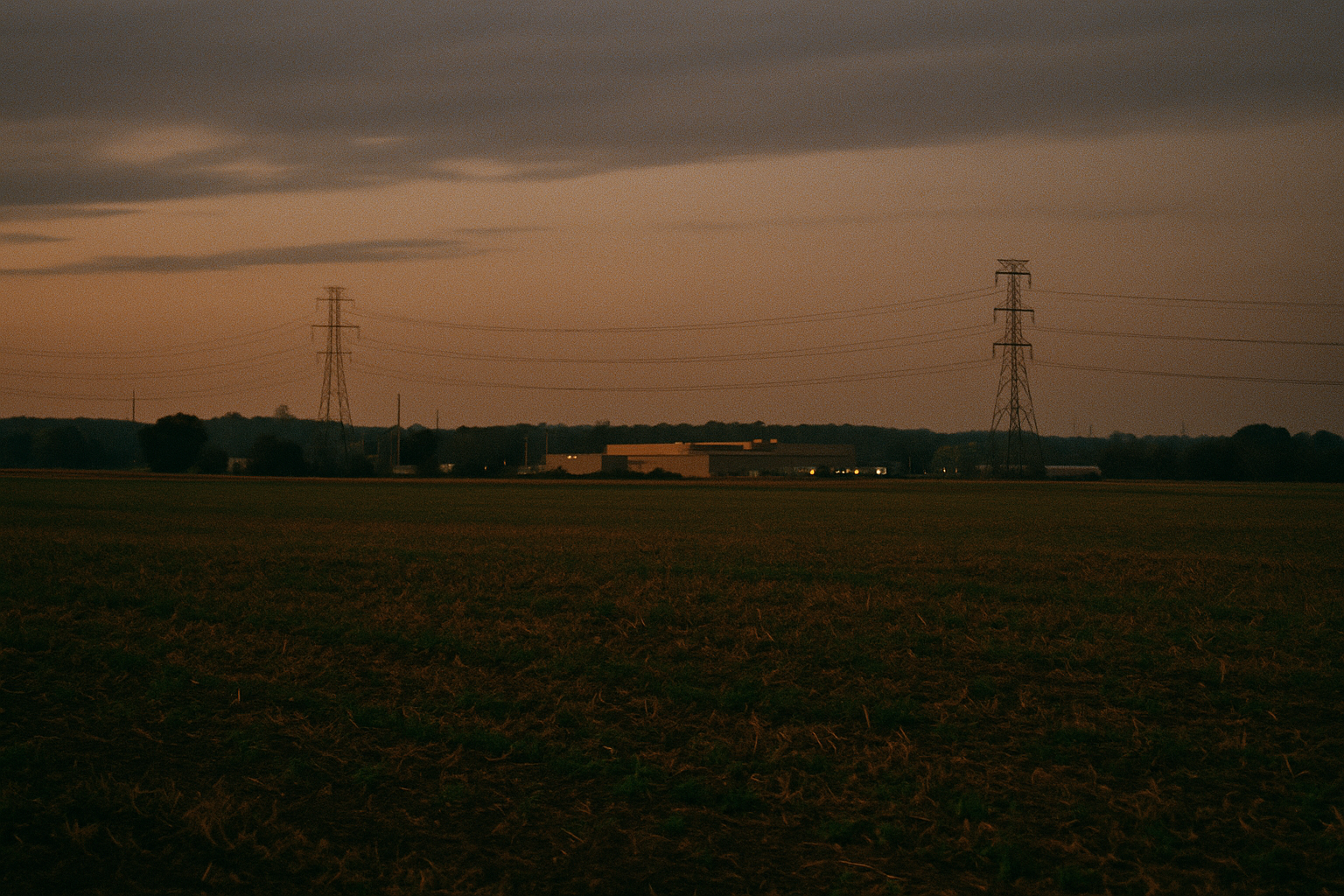 Cover image for When Data Centers Target Farmland showing rural farmland at dusk with distant utility infrastructure and a low industrial campus on the horizon, open field foreground, subtle tension between agriculture and development.